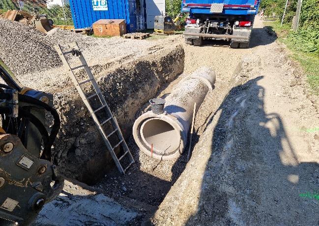 Bauarbeiten am Entlastungskanal Greimelstraße in Übersee, Bayern, mit Baustellenfahrzeugen und Wasserbauarbeiten.