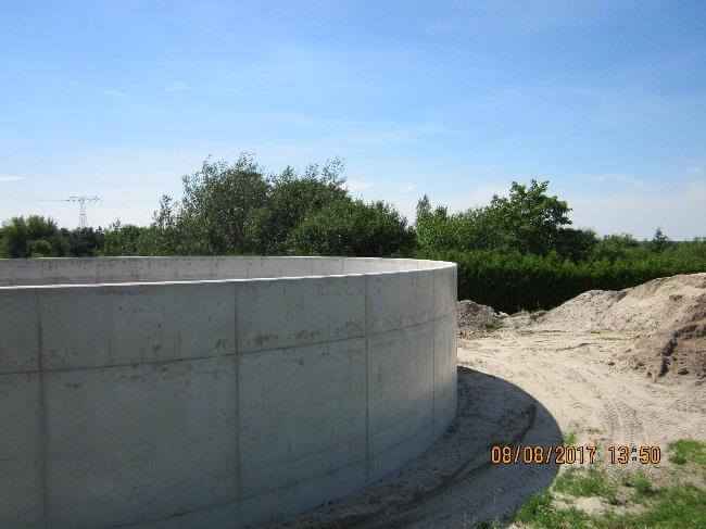 Bauarbeiten am Mischwasserspeicher der Kläranlage Gräfenhainichen, mit Baustellenfahrzeugen und Bauarbeitern im Einsatz.