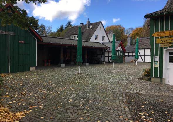 Ansicht der neu gestalteten Freianlage des Heimatmuseums in Reichshof, mit Sitzgelegenheiten und Pflanzen.